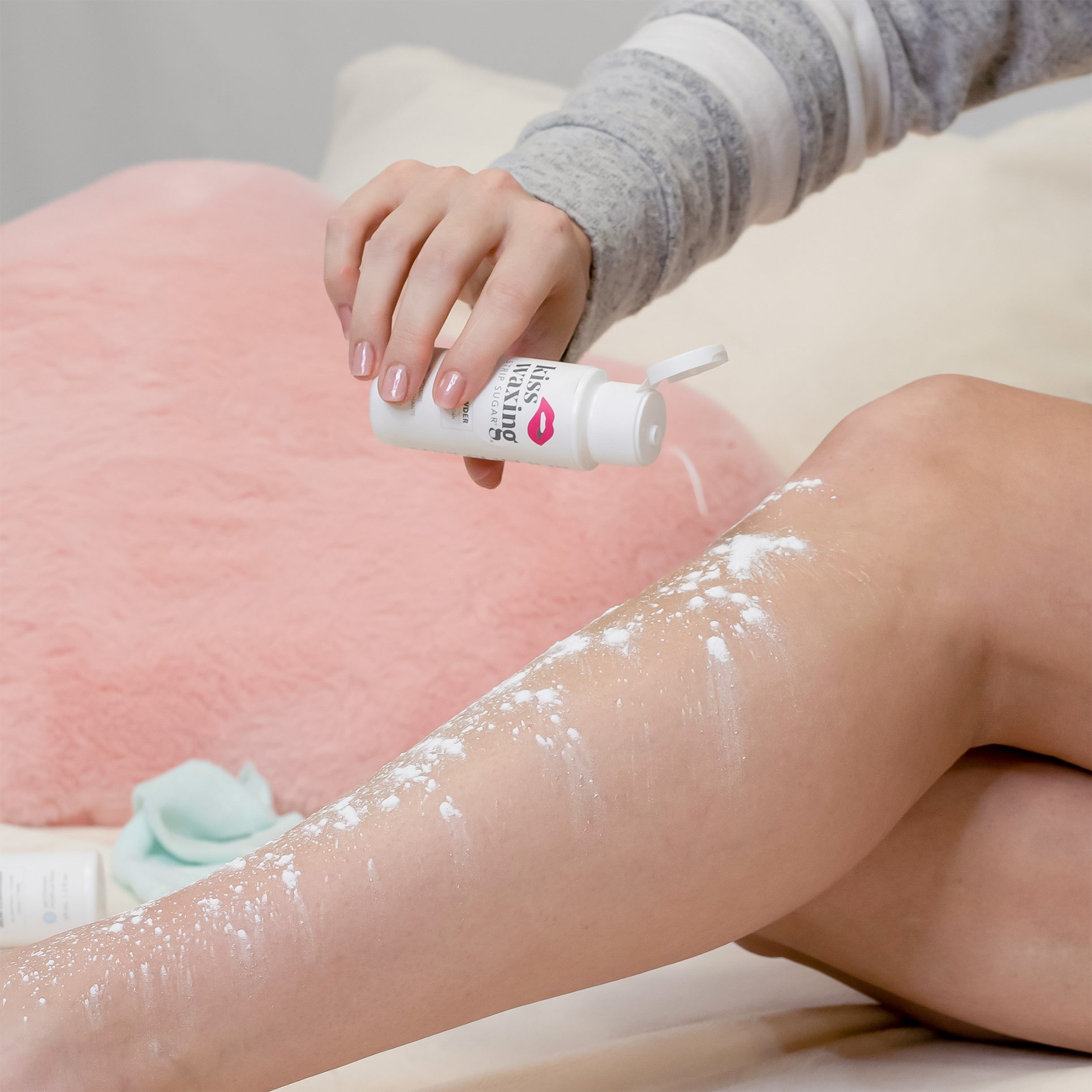 Person applying kiss waxing skin powder to their legs