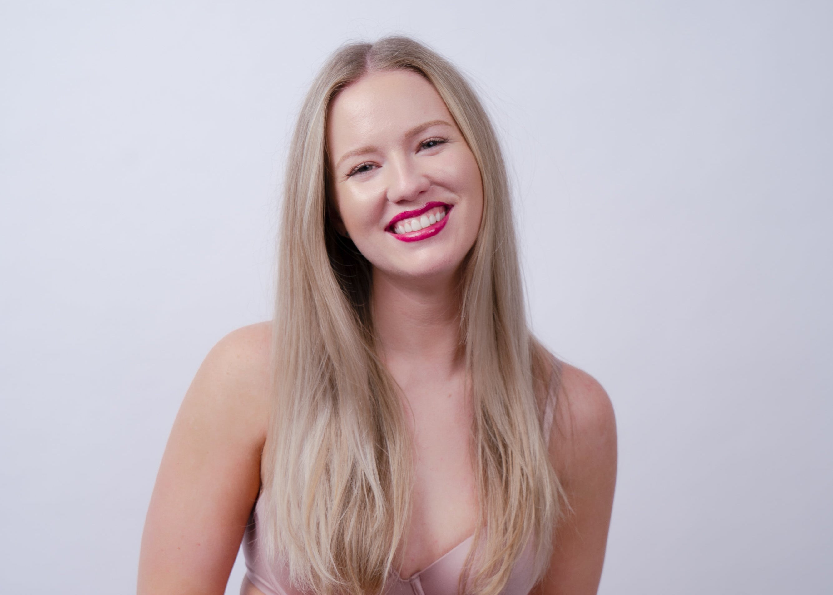 Woman wearing a pink lingerie set against a plain background