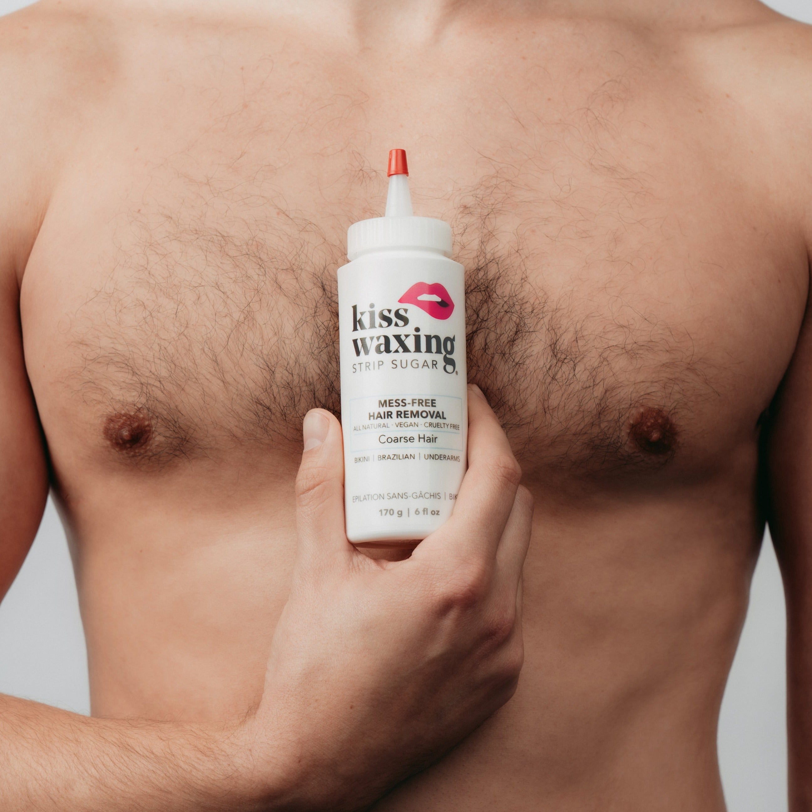 Man holding a bottle of 'kiss waxing' coarse strip sugar in front of his chest