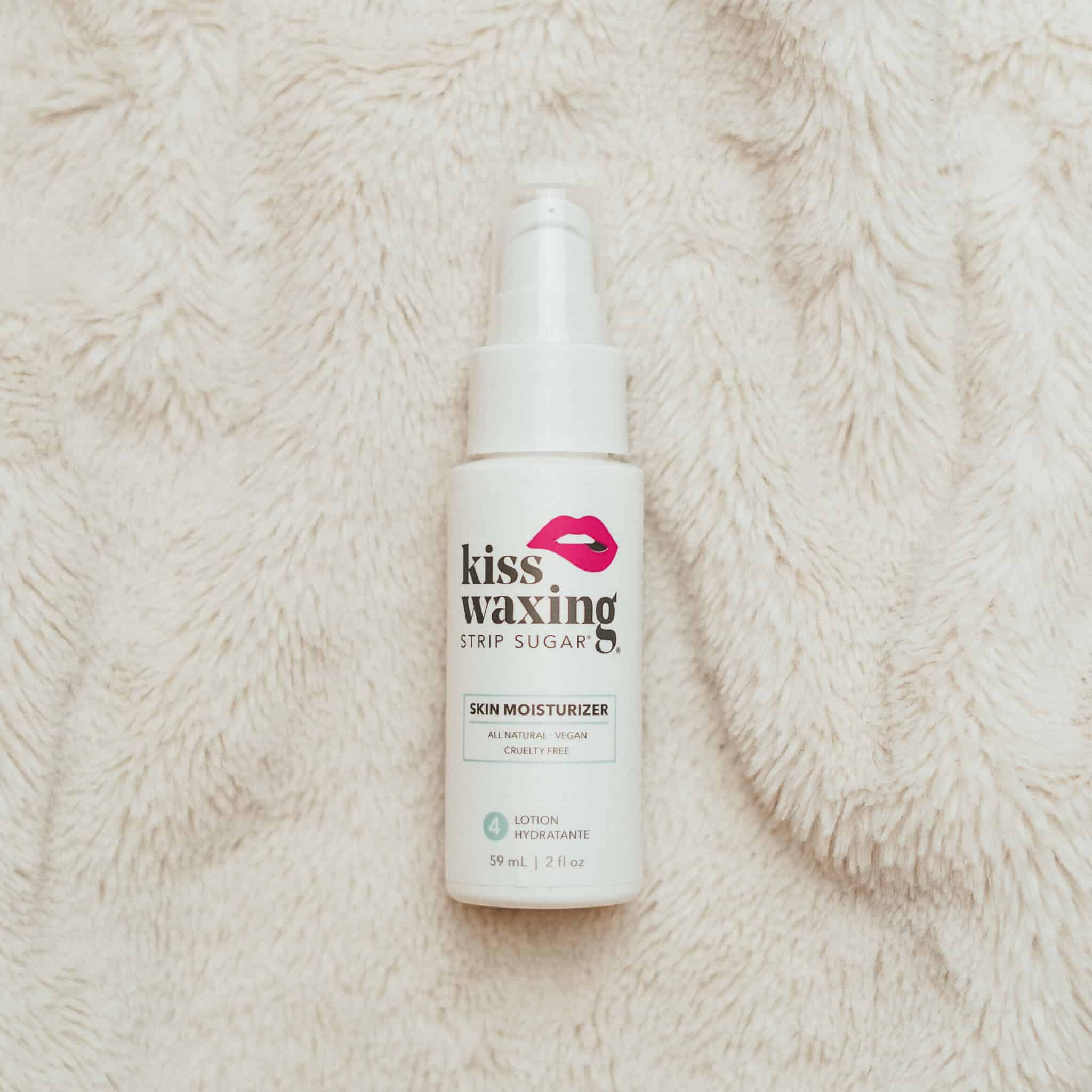 Bottle of 'kiss waxing' strip sugar skin moisturizer on a textured beige surface