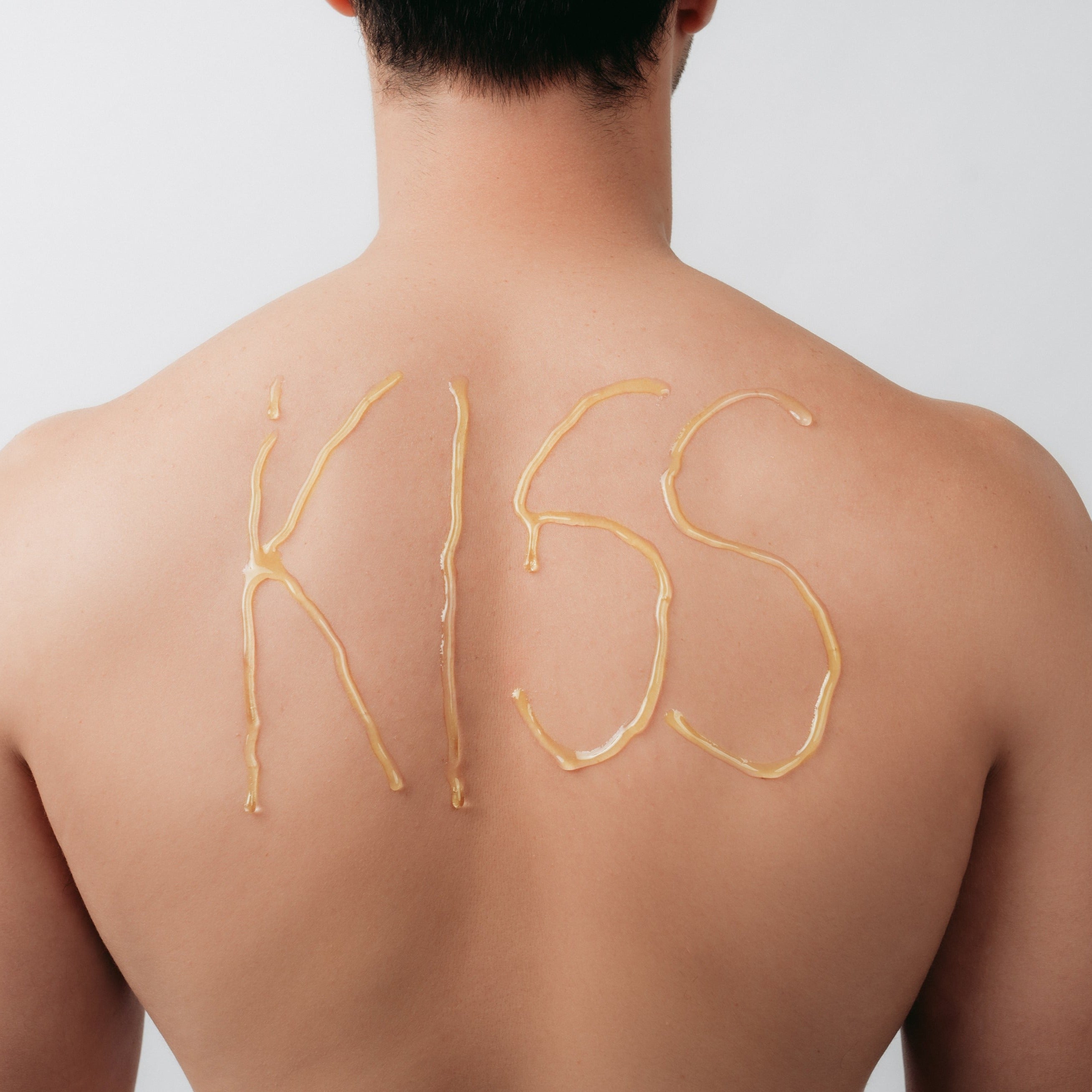 Kiss Waxing strip sugar spelling 'KISS' on a man's back against a plain background