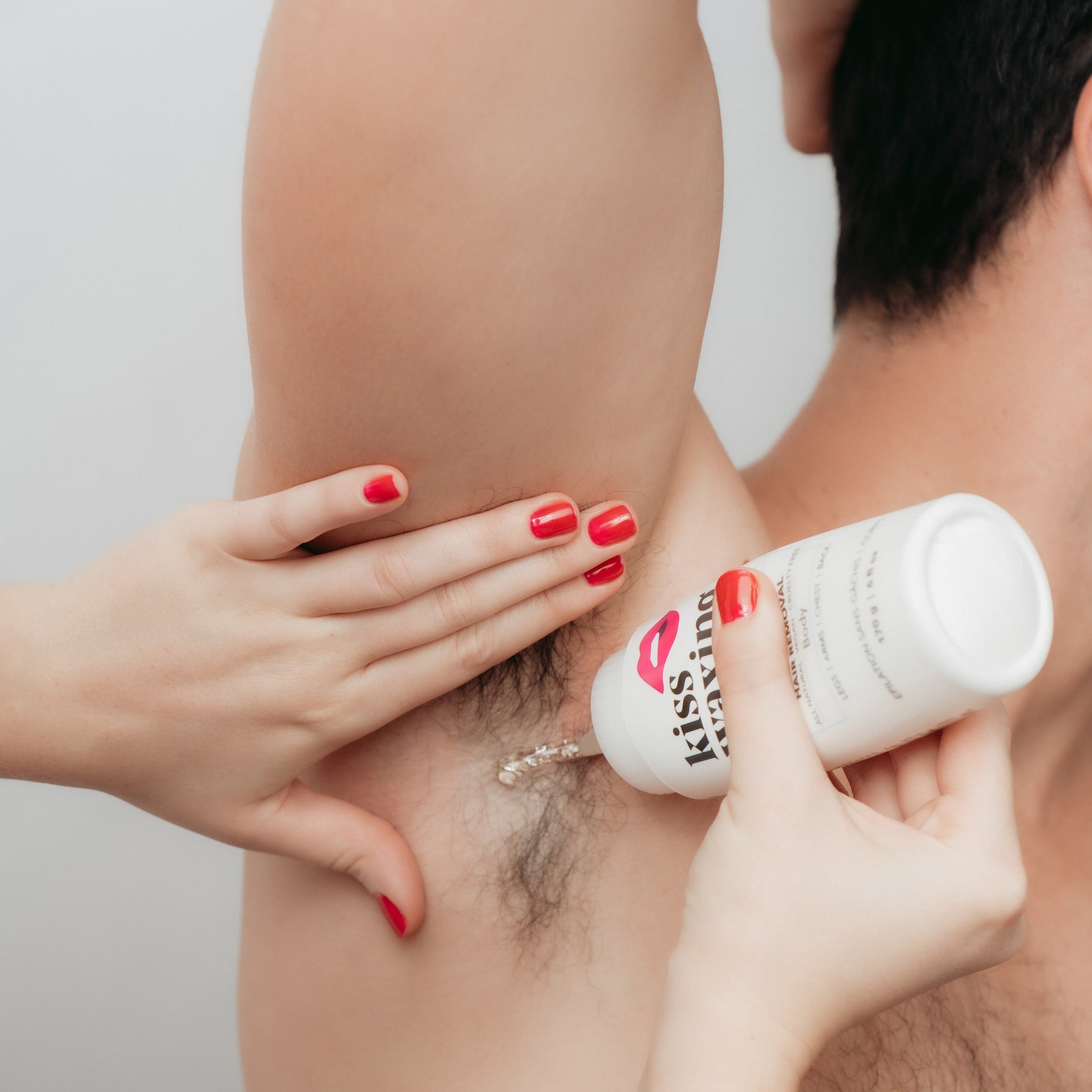 Person applying kiss waxing strip sugar to a man's underarm