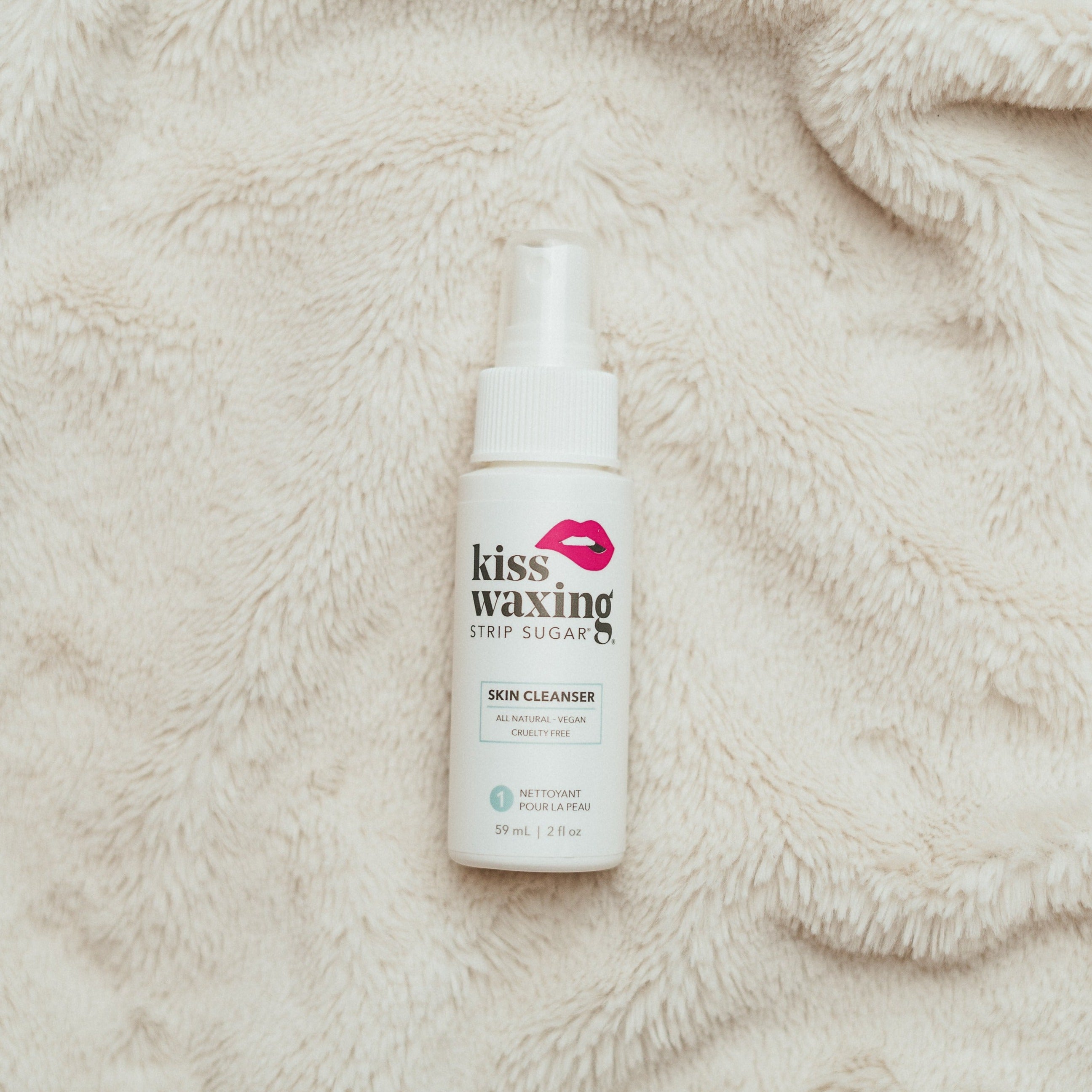 Bottle of kiss waxing skin cleanser on a textured beige surface