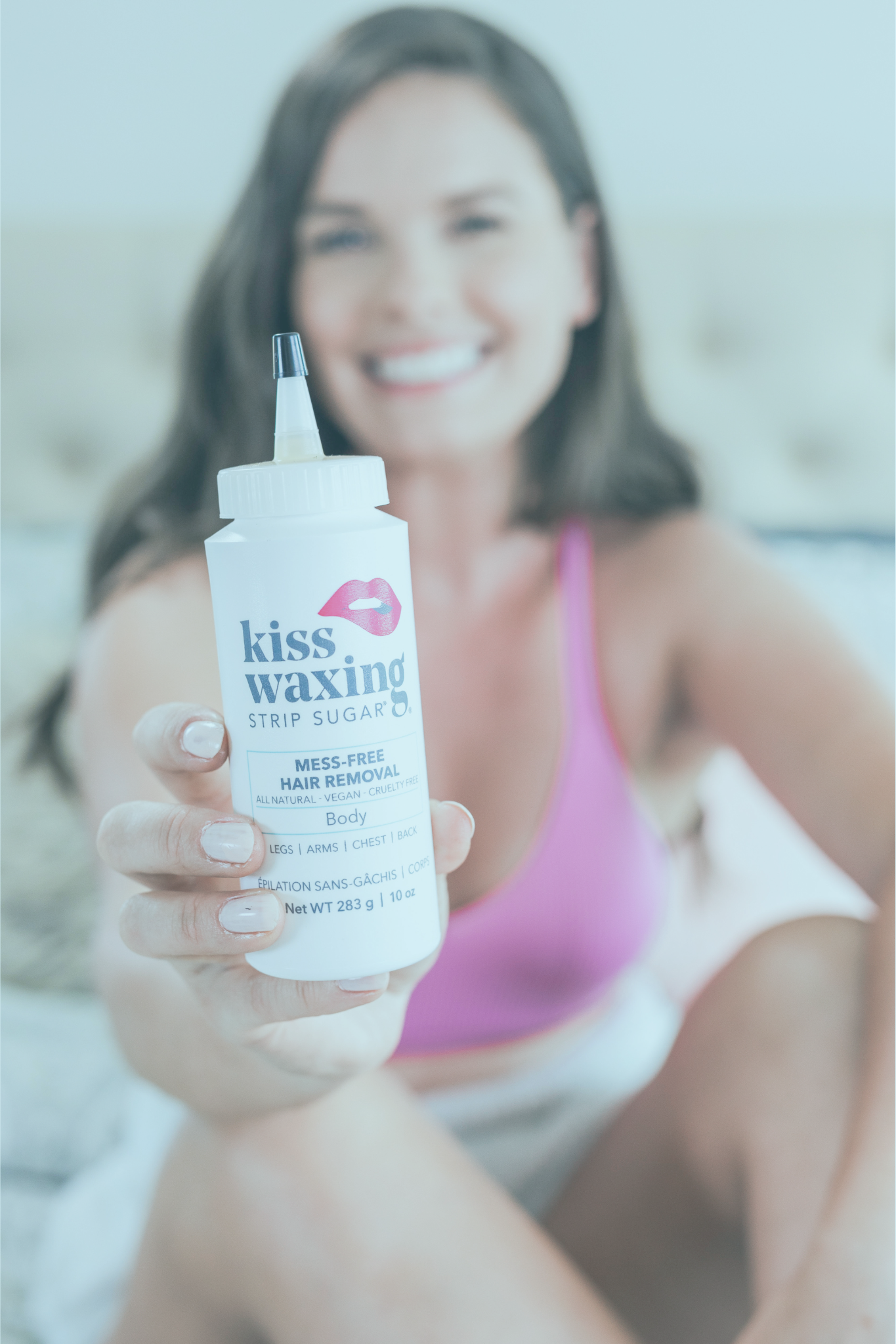 Woman holding a bottle of 'kiss waxing strip sugar' with a blurred background