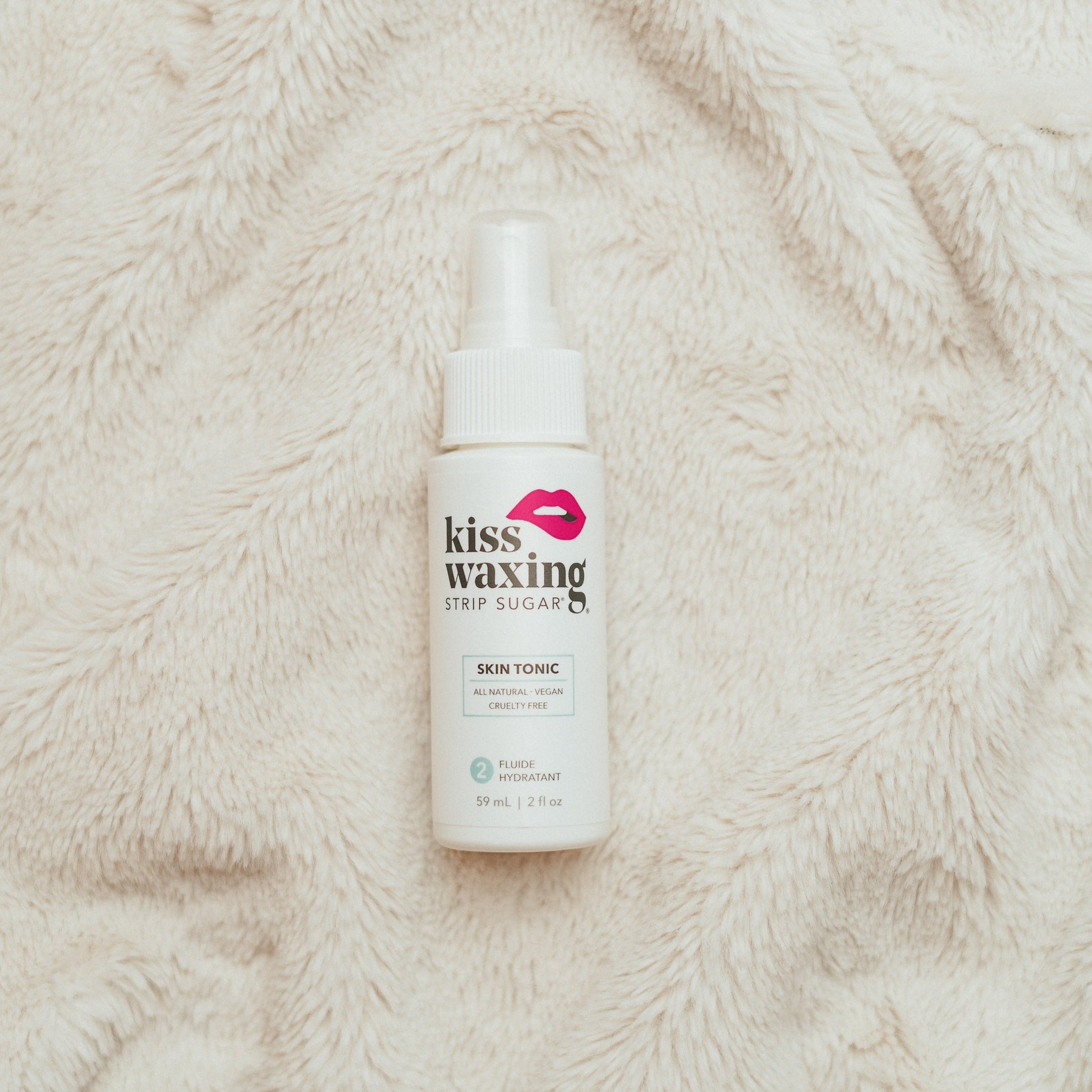 Bottle of kiss waxing skin tonic on a textured beige surface